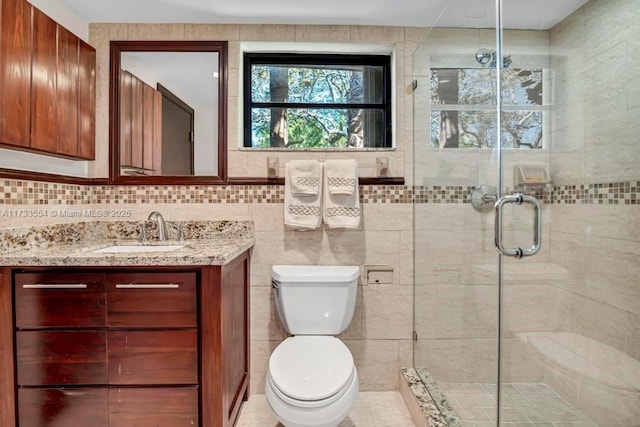 bathroom with vanity, tile walls, toilet, and walk in shower