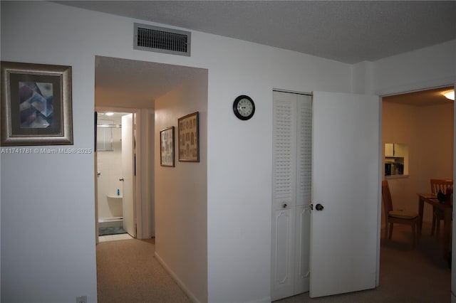 corridor featuring carpet floors and a textured ceiling