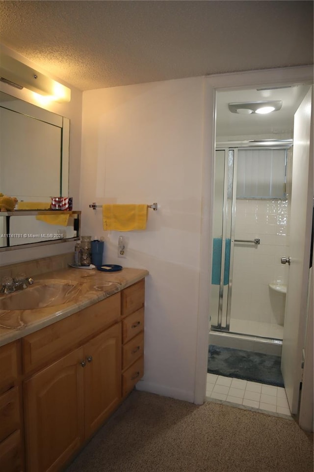 bathroom with vanity, tile patterned flooring, a shower with door, and a textured ceiling