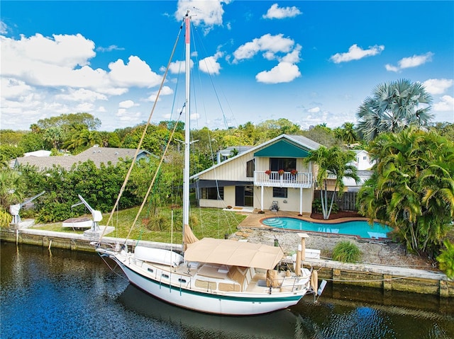 rear view of property featuring a water view, a balcony, and a patio area