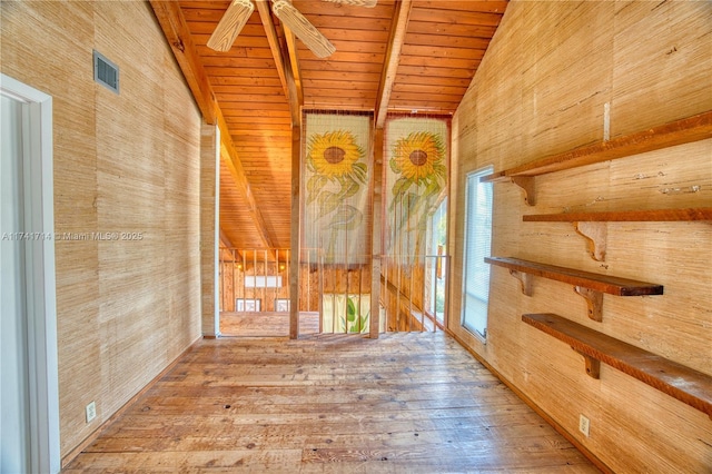 interior space with wood walls, wood ceiling, vaulted ceiling with beams, hardwood / wood-style flooring, and ceiling fan