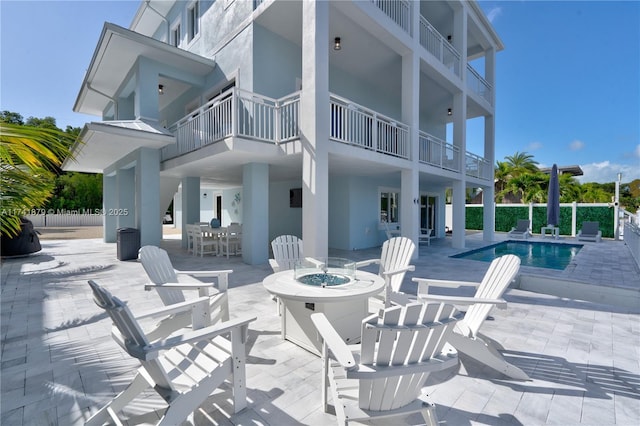 back of property with a fenced in pool, a patio area, and an outdoor fire pit