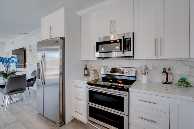 kitchen featuring white cabinetry, light stone counters, tasteful backsplash, and appliances with stainless steel finishes