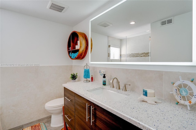 bathroom featuring vanity, toilet, and tile walls