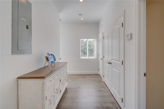 corridor with electric panel and light hardwood / wood-style flooring