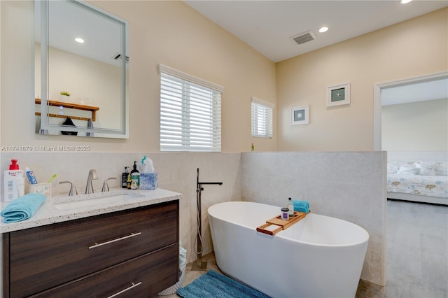 bathroom featuring vanity, tile walls, and a tub