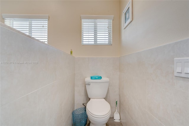 bathroom with toilet and tile walls