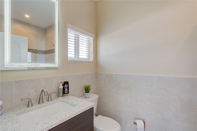 bathroom with vanity, tile walls, and toilet