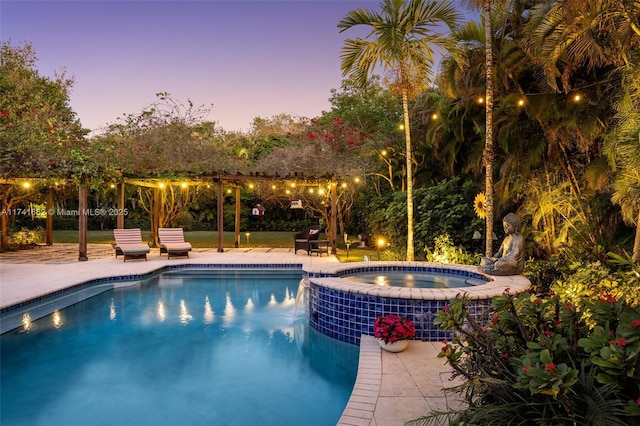 pool at dusk featuring a patio and an in ground hot tub