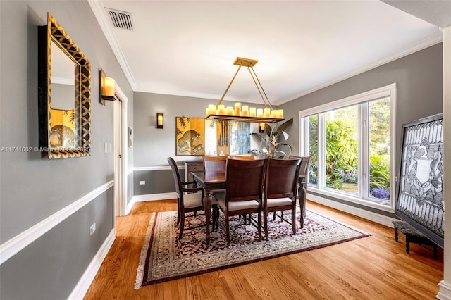 dining room featuring hardwood / wood-style flooring, ornamental molding, and a chandelier