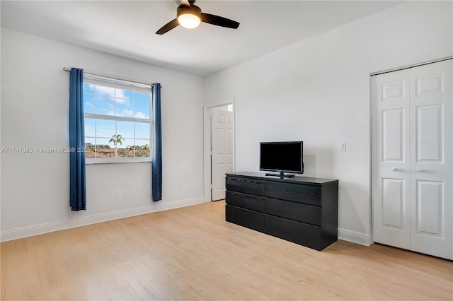 bedroom with light wood finished floors, a closet, a ceiling fan, and baseboards