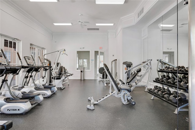 exercise room with visible vents, baseboards, ornamental molding, a towering ceiling, and a ceiling fan