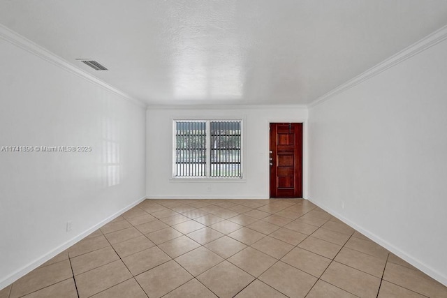 empty room with light tile patterned floors, baseboards, visible vents, and crown molding