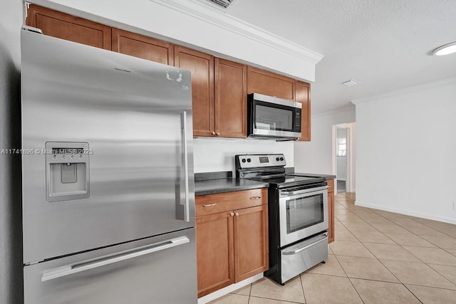 kitchen featuring crown molding, light tile patterned floors, stainless steel appliances, dark countertops, and brown cabinetry