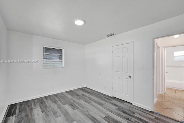 spare room with wood finished floors, visible vents, and baseboards