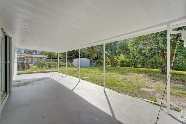 view of patio / terrace with a carport, a shed, a fenced backyard, and an outbuilding