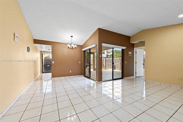 empty room with lofted ceiling, a textured ceiling, an inviting chandelier, and light tile patterned flooring