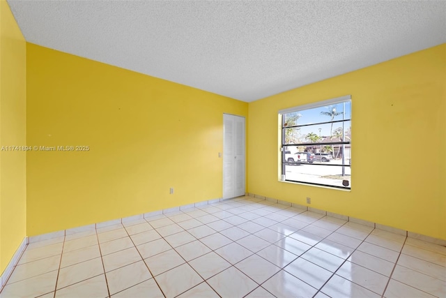 empty room featuring light tile patterned flooring and a textured ceiling