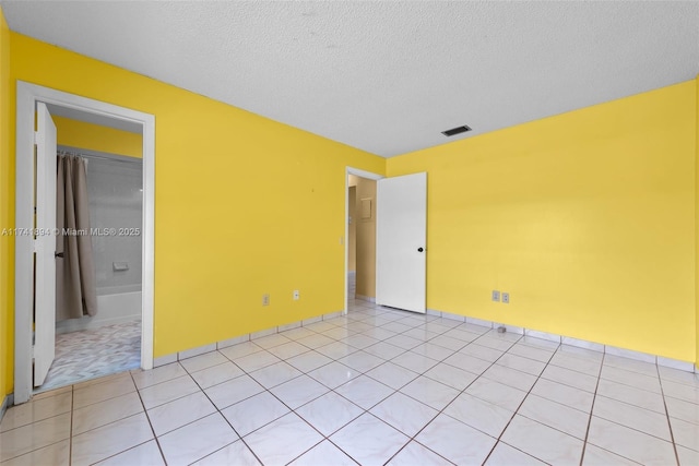 tiled spare room featuring a textured ceiling