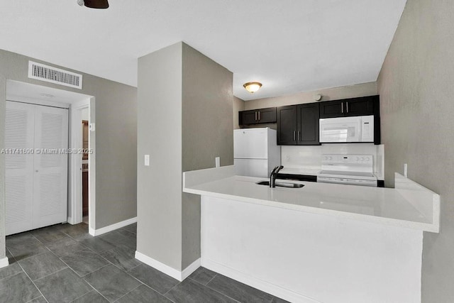 kitchen with white appliances, kitchen peninsula, and sink