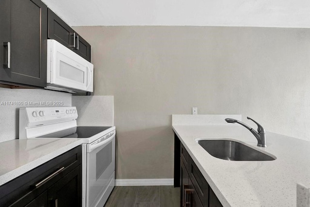 kitchen with light stone counters, white appliances, and sink