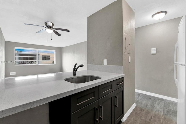 kitchen featuring white refrigerator, ceiling fan, light stone countertops, and sink