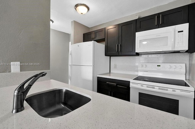 kitchen with sink, light stone counters, and white appliances