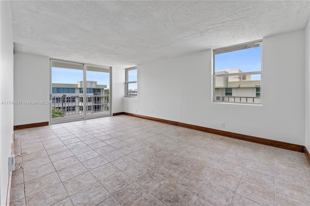 empty room with expansive windows and a textured ceiling