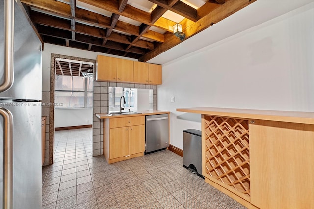 kitchen with light brown cabinetry, sink, decorative backsplash, kitchen peninsula, and stainless steel appliances