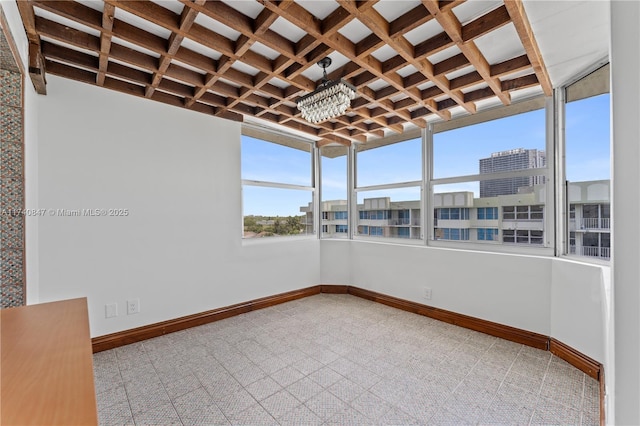 unfurnished sunroom with coffered ceiling, beam ceiling, and a notable chandelier