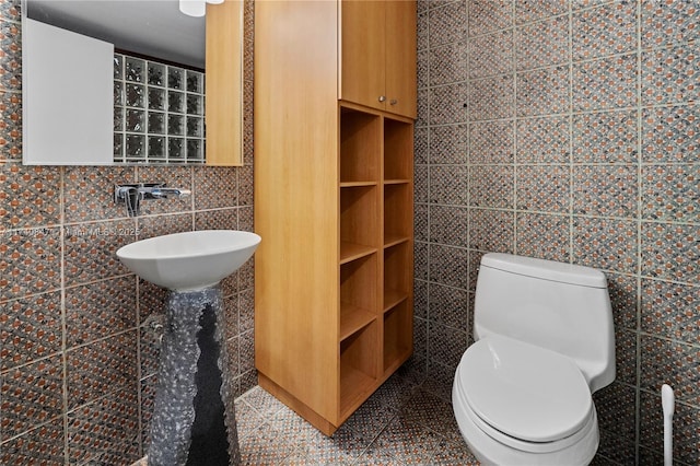 bathroom with sink, tile walls, and toilet