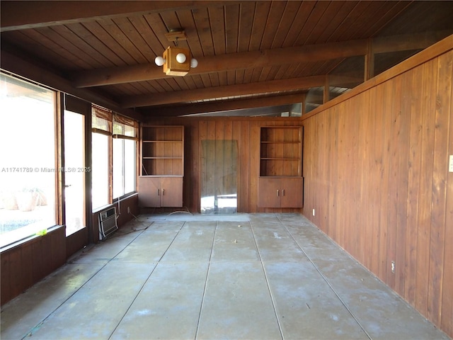 interior space with beam ceiling, a wall unit AC, wood ceiling, and a wealth of natural light