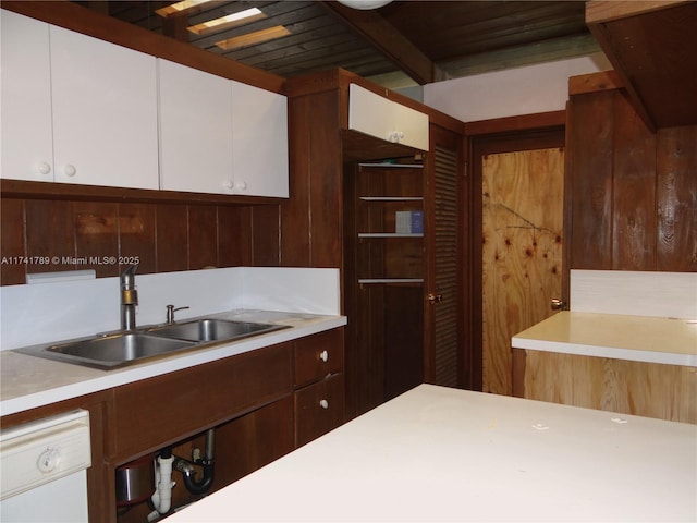 kitchen featuring white cabinetry, sink, white dishwasher, and beam ceiling