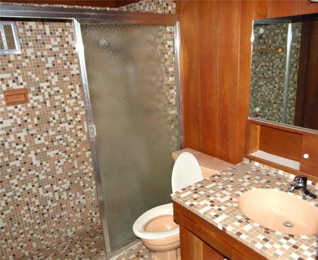 bathroom featuring toilet, vanity, and a shower with shower door