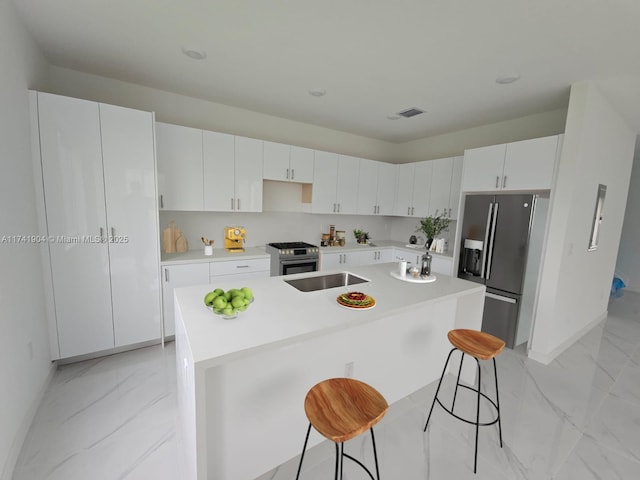 kitchen featuring white cabinetry, a kitchen island with sink, refrigerator with ice dispenser, and stainless steel gas stove