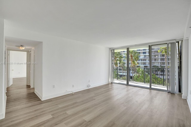 empty room with a wall of windows and light hardwood / wood-style flooring