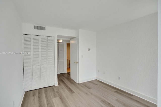 unfurnished bedroom with light hardwood / wood-style floors and a closet