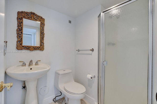 bathroom with sink, a shower with door, and toilet