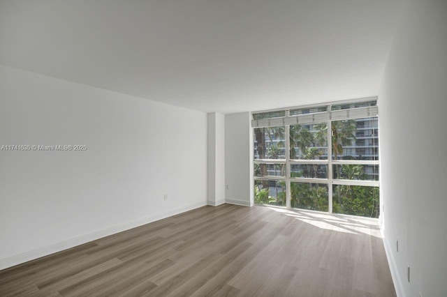 unfurnished room with floor to ceiling windows and hardwood / wood-style floors