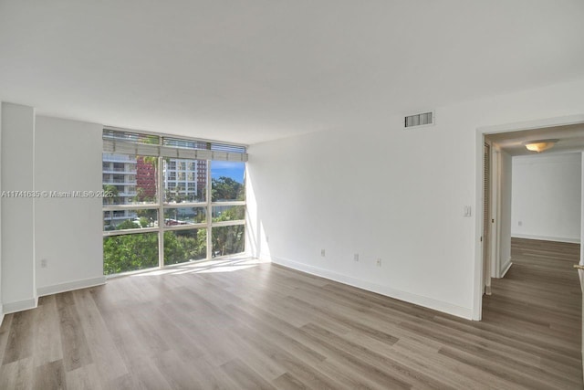 unfurnished room with expansive windows and light wood-type flooring