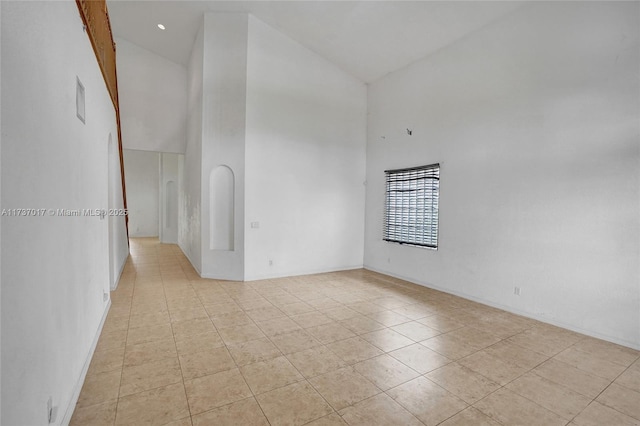 empty room with high vaulted ceiling and light tile patterned floors