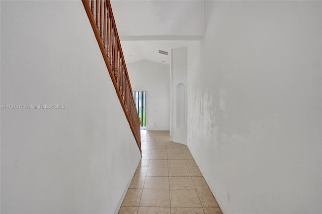 hallway featuring light tile patterned floors and high vaulted ceiling