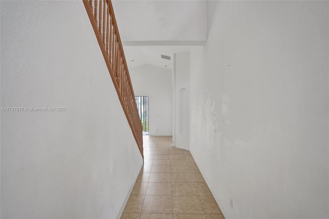 hall with high vaulted ceiling and light tile patterned floors