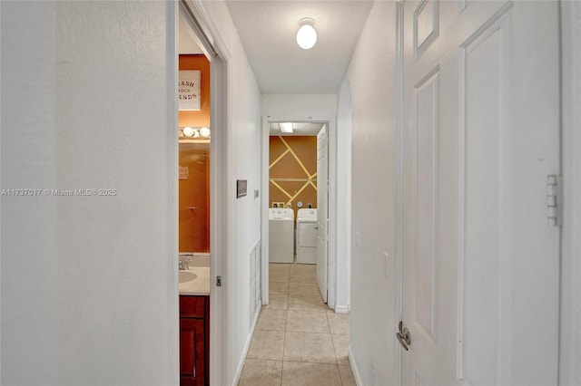 hallway featuring sink, washer and dryer, and light tile patterned floors