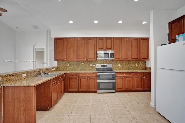 kitchen featuring sink, appliances with stainless steel finishes, backsplash, light stone countertops, and kitchen peninsula