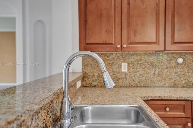 interior details with light stone countertops, sink, and backsplash