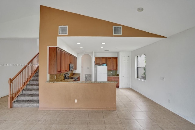 kitchen with vaulted ceiling, light tile patterned flooring, tasteful backsplash, kitchen peninsula, and stainless steel appliances