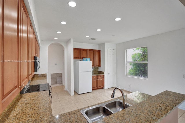 kitchen featuring white refrigerator, sink, electric range oven, and light stone counters