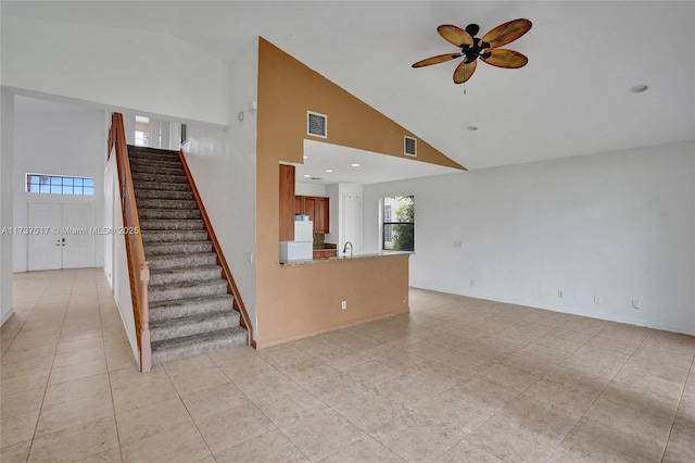 unfurnished living room with ceiling fan, sink, high vaulted ceiling, and light tile patterned floors