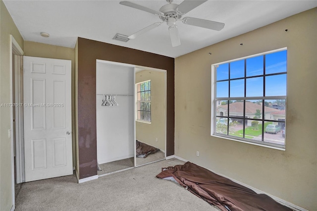 unfurnished bedroom with light colored carpet, a closet, and ceiling fan